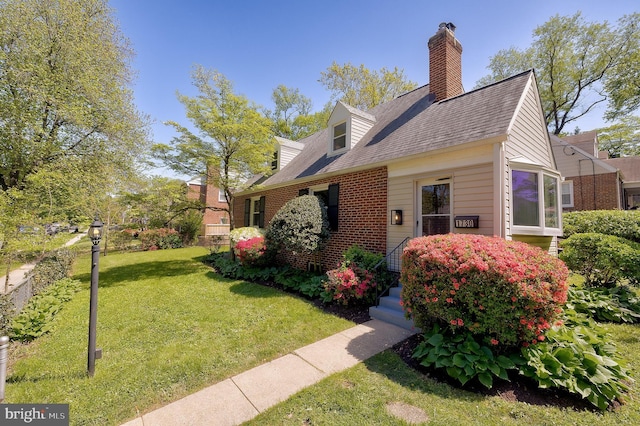 view of front of house with brick siding, a chimney, roof with shingles, and a front lawn