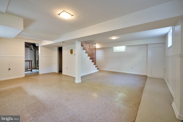 below grade area featuring baseboards and stairs