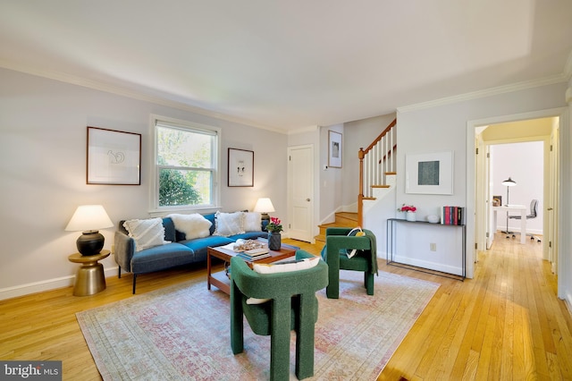 living area featuring baseboards, ornamental molding, light wood-style flooring, and stairway