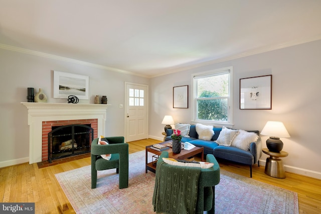living room featuring baseboards, ornamental molding, a fireplace, and light wood-type flooring