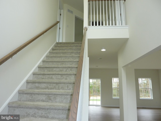 stairway featuring plenty of natural light, visible vents, baseboards, and wood finished floors