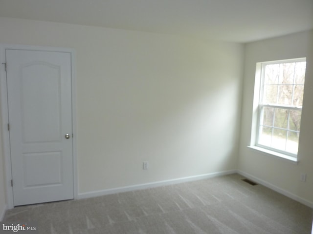 unfurnished room with light colored carpet, baseboards, and visible vents