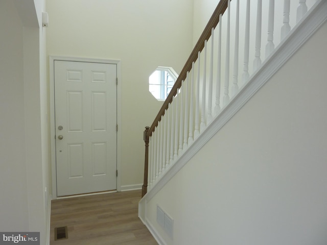 foyer entrance featuring stairway, visible vents, baseboards, and wood finished floors