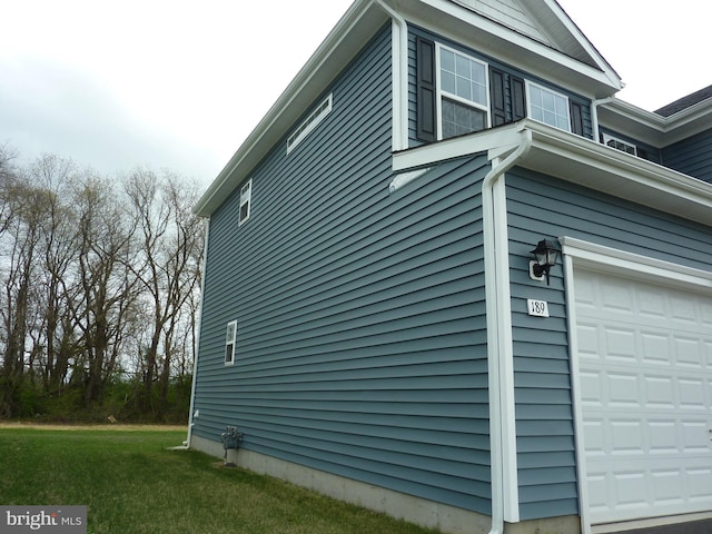 view of property exterior with a garage and a lawn