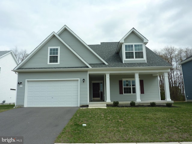 view of front of home with a front lawn, covered porch, driveway, and roof with shingles