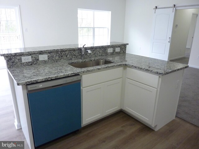 kitchen with dark wood finished floors, light stone countertops, white cabinets, dishwasher, and a sink
