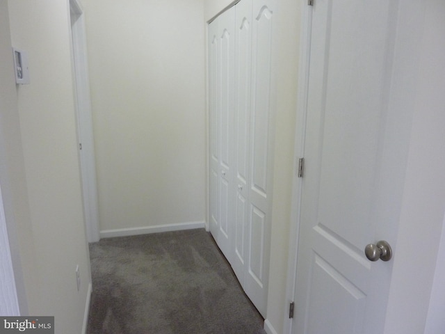 corridor with dark carpet and baseboards