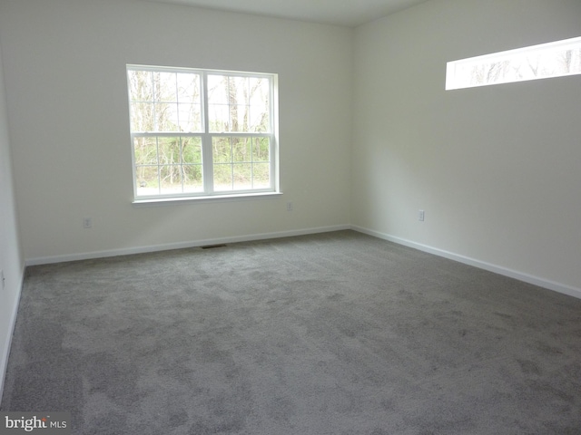 spare room featuring baseboards, visible vents, and carpet floors