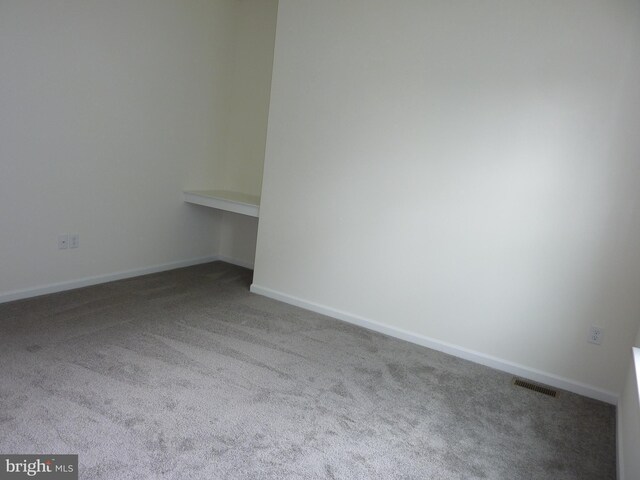 carpeted empty room with visible vents and baseboards