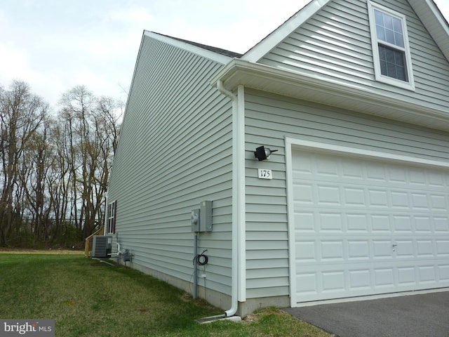 view of home's exterior with central air condition unit, a garage, and a lawn