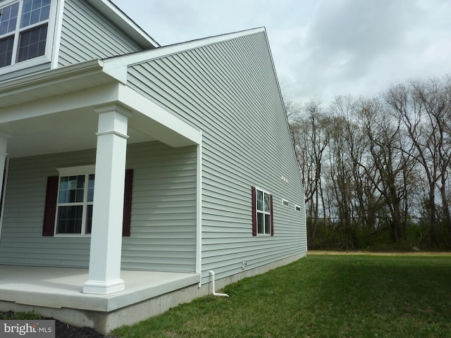 view of side of home featuring covered porch and a lawn