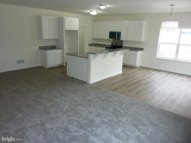 kitchen with a center island, white cabinets, visible vents, a breakfast bar area, and stainless steel range with electric cooktop