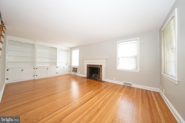 7411 Elizabeth Rd, Elkins Park, PA 19027 - unfurnished living room featuring a brick fireplace, light wood-type flooring, plenty of natural light, and baseboards