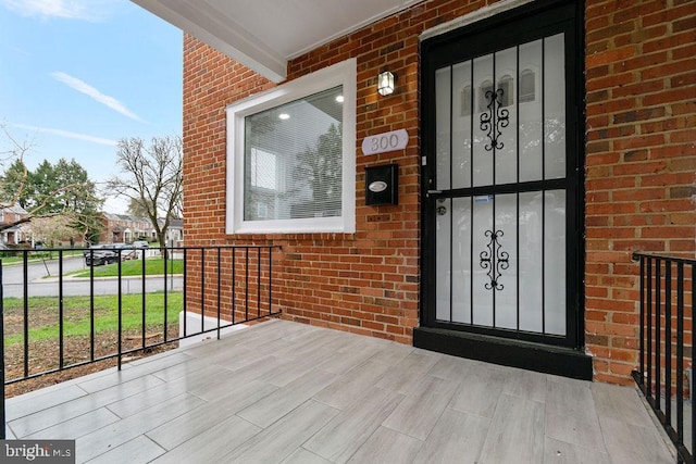 300 Denison St, Baltimore, MD 21229 - doorway to property featuring brick siding and covered porch