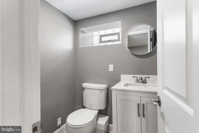 half bath with vanity, toilet, and baseboards