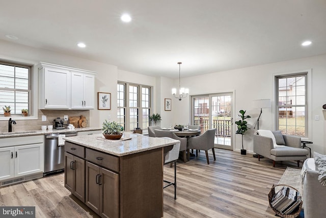 610 Greenbriar Path, Cochranville, PA 19330 - kitchen with stainless steel dishwasher, a chandelier, light wood-style flooring, a breakfast bar area, and white cabinetry