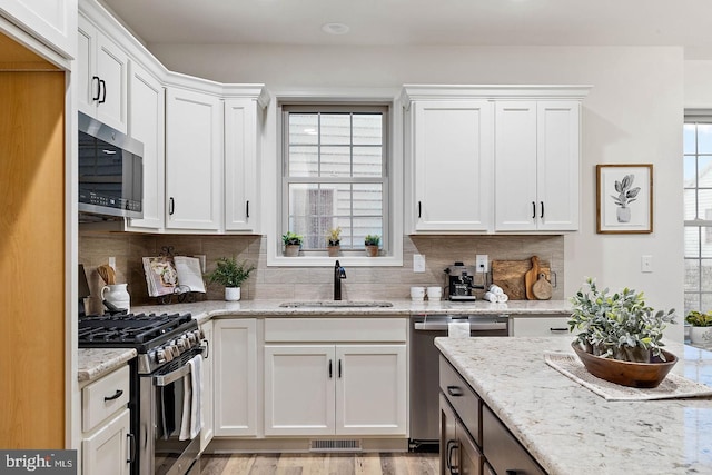 610 Greenbriar Path, Cochranville, PA 19330 - kitchen featuring stainless steel appliances, white cabinets, backsplash, light stone countertops, and light wood-type flooring