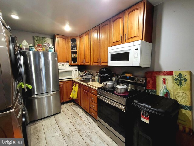 3149 Jasper St, Philadelphia, PA 19134 - kitchen with light wood finished floors, glass insert cabinets, brown cabinetry, appliances with stainless steel finishes, and recessed lighting