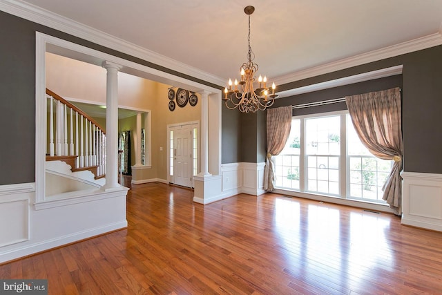 interior space featuring wood finished floors, a notable chandelier, ornamental molding, and a wainscoted wall