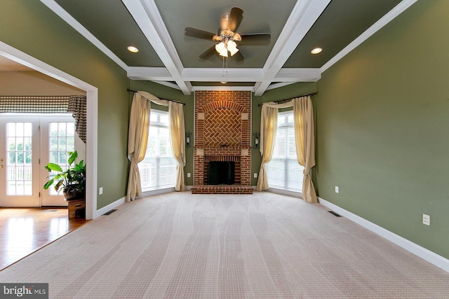unfurnished living room with beam ceiling, a wealth of natural light, a ceiling fan, and baseboards