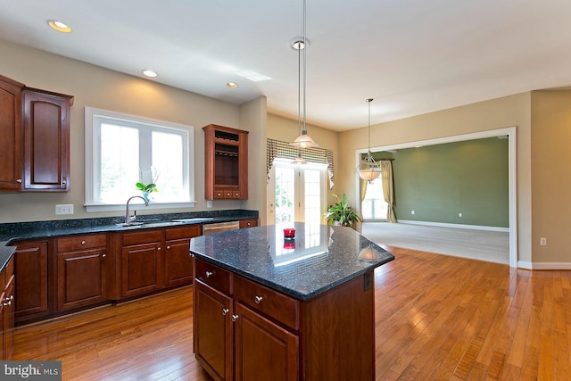 kitchen with a healthy amount of sunlight, stainless steel dishwasher, light wood-style floors, and a kitchen island