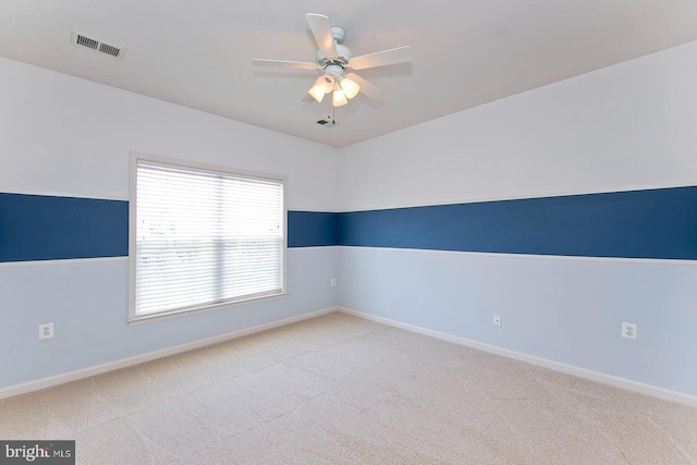 carpeted spare room with visible vents, baseboards, and ceiling fan