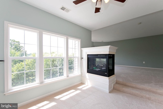 unfurnished living room with baseboards, carpet floors, visible vents, a healthy amount of sunlight, and ceiling fan