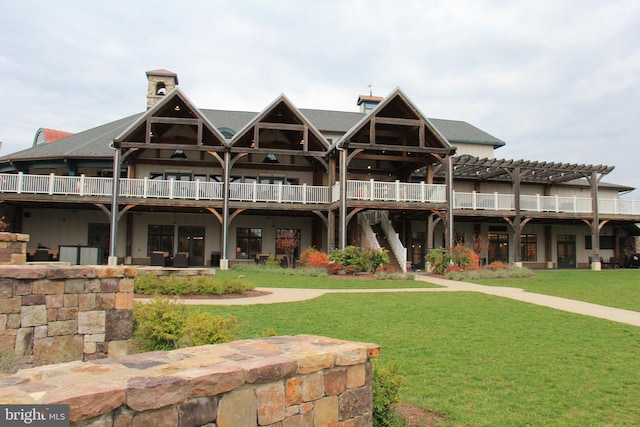 back of house featuring a chimney, a pergola, and a lawn