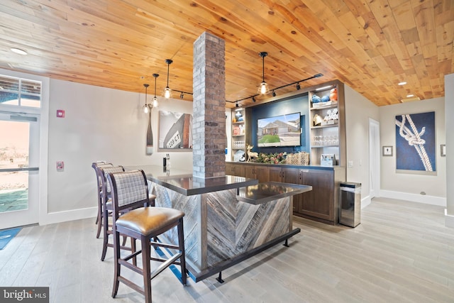 bar with light wood-type flooring, ornate columns, baseboards, and wood ceiling