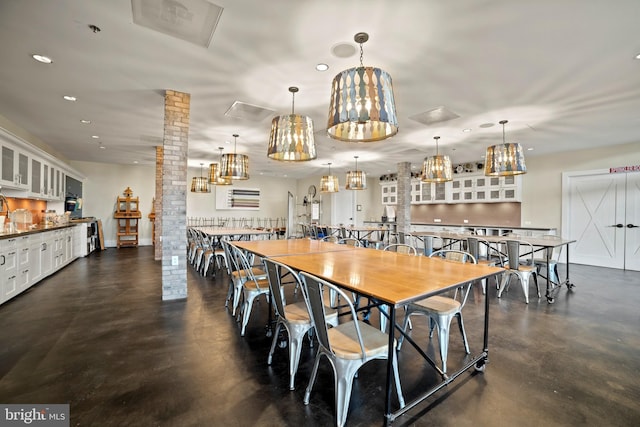 dining room featuring finished concrete floors, decorative columns, an inviting chandelier, and recessed lighting