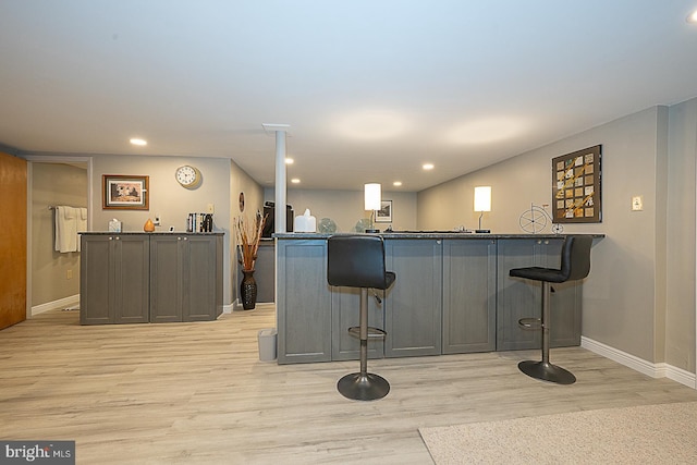 101 Andrea Rd, Cheltenham, PA 19012 - kitchen featuring light wood finished floors, a kitchen bar, baseboards, a peninsula, and dark countertops