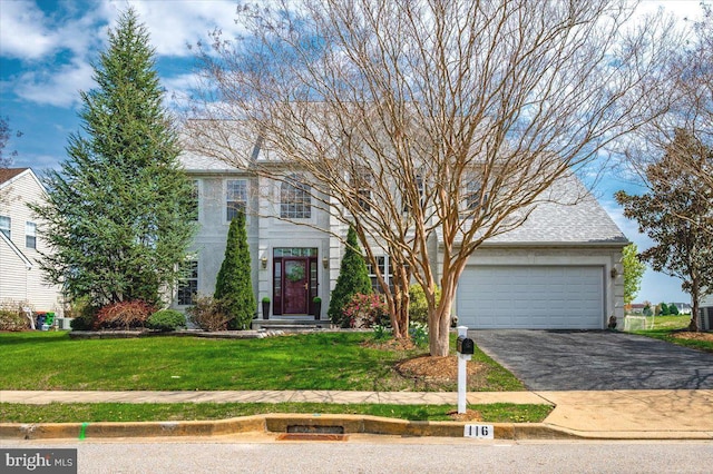 colonial-style house with driveway, a garage, and a front lawn