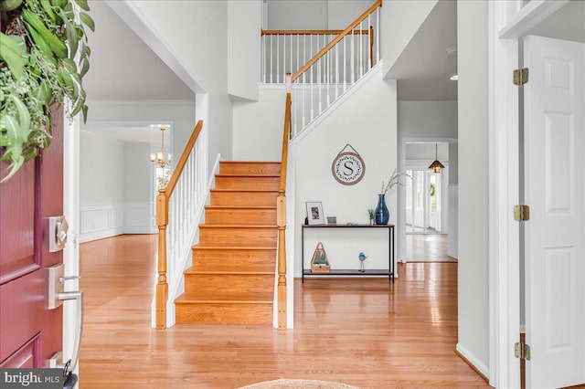entryway with stairway, ornamental molding, a wainscoted wall, and wood finished floors