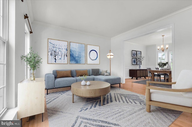 living area featuring a notable chandelier, crown molding, and wood finished floors
