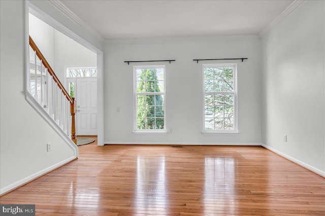 unfurnished living room featuring stairway, light wood-style floors, baseboards, and crown molding