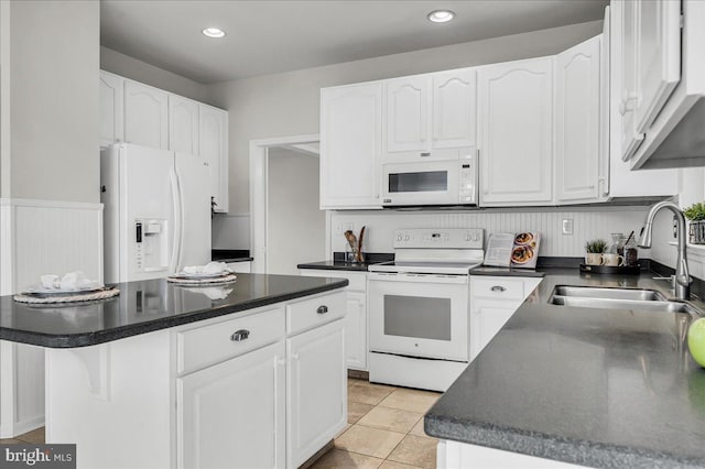 kitchen featuring white cabinets, white appliances, a sink, and dark countertops