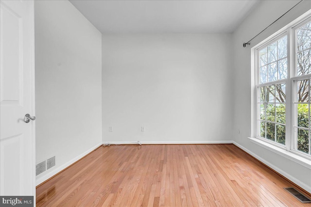 spare room featuring light wood-style flooring, baseboards, and visible vents