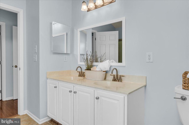 bathroom with a sink, baseboards, and double vanity