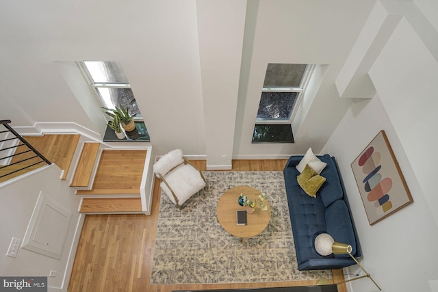 living room featuring a skylight, wood finished floors, and baseboards