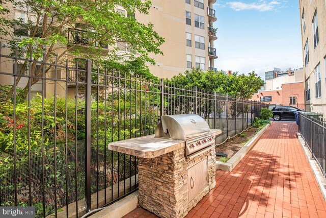 view of patio / terrace featuring a grill, fence, and exterior kitchen