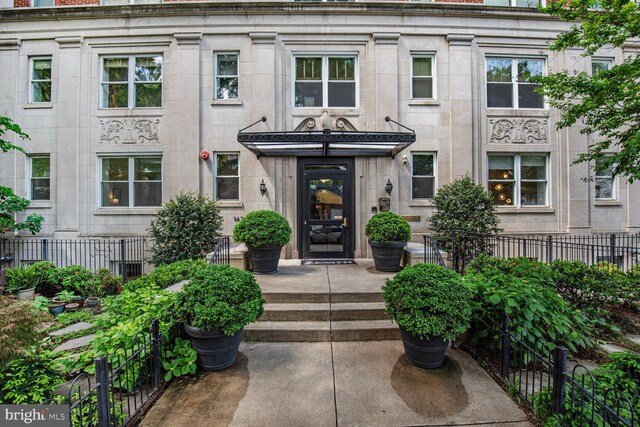 property entrance featuring stone siding and fence