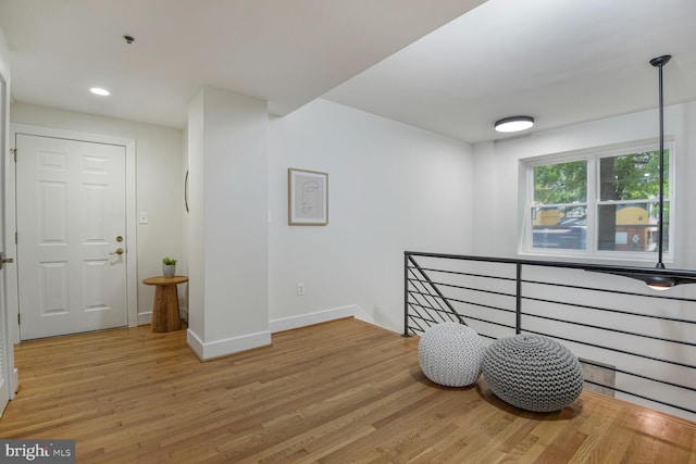 corridor with an upstairs landing, light wood-style flooring, baseboards, and recessed lighting