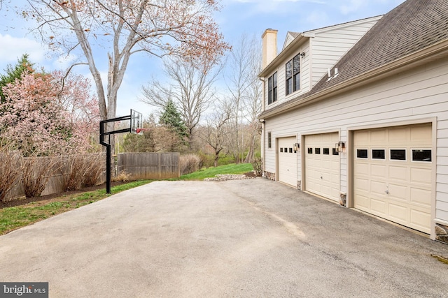 607 Newtown Rd, Berwyn, PA 19312 - view of property exterior featuring fence, a shingled roof, a garage, a chimney, and driveway