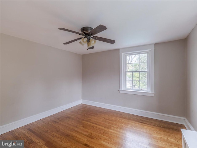 unfurnished room with a ceiling fan, baseboards, and light wood-type flooring