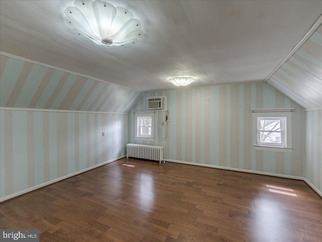 additional living space with wallpapered walls, wood finished floors, radiator heating unit, and vaulted ceiling