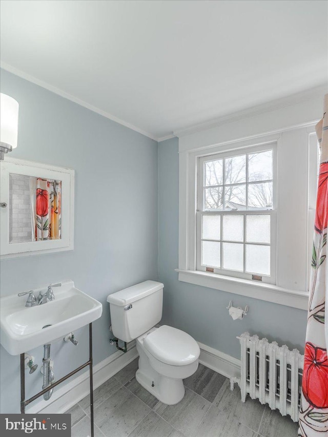 bathroom with crown molding, toilet, a sink, radiator, and baseboards