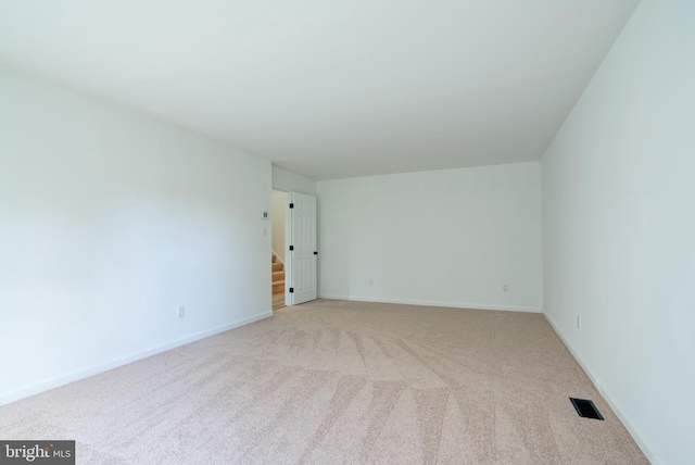 empty room featuring light colored carpet, baseboards, and visible vents