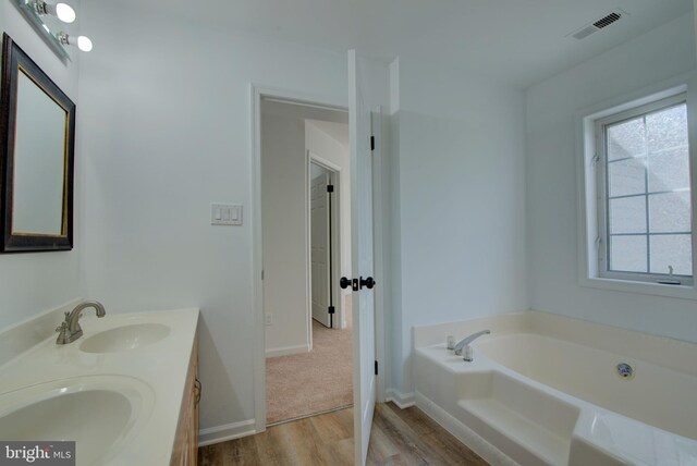 bathroom featuring a bath, double vanity, a sink, and visible vents