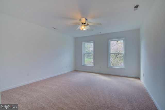 empty room featuring light carpet, ceiling fan, baseboards, and visible vents