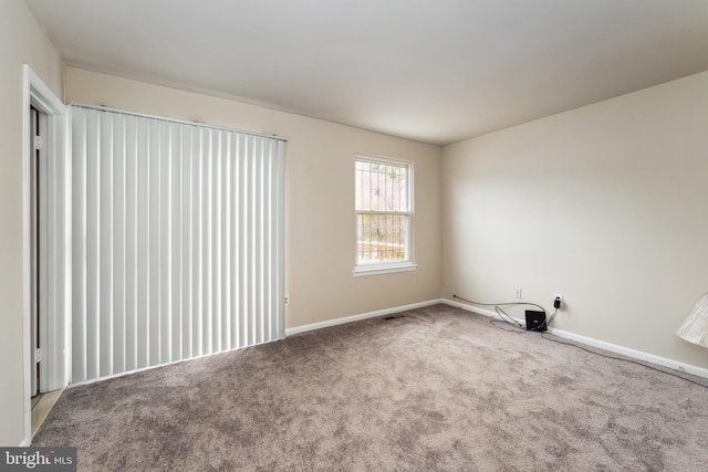 carpeted empty room featuring baseboards